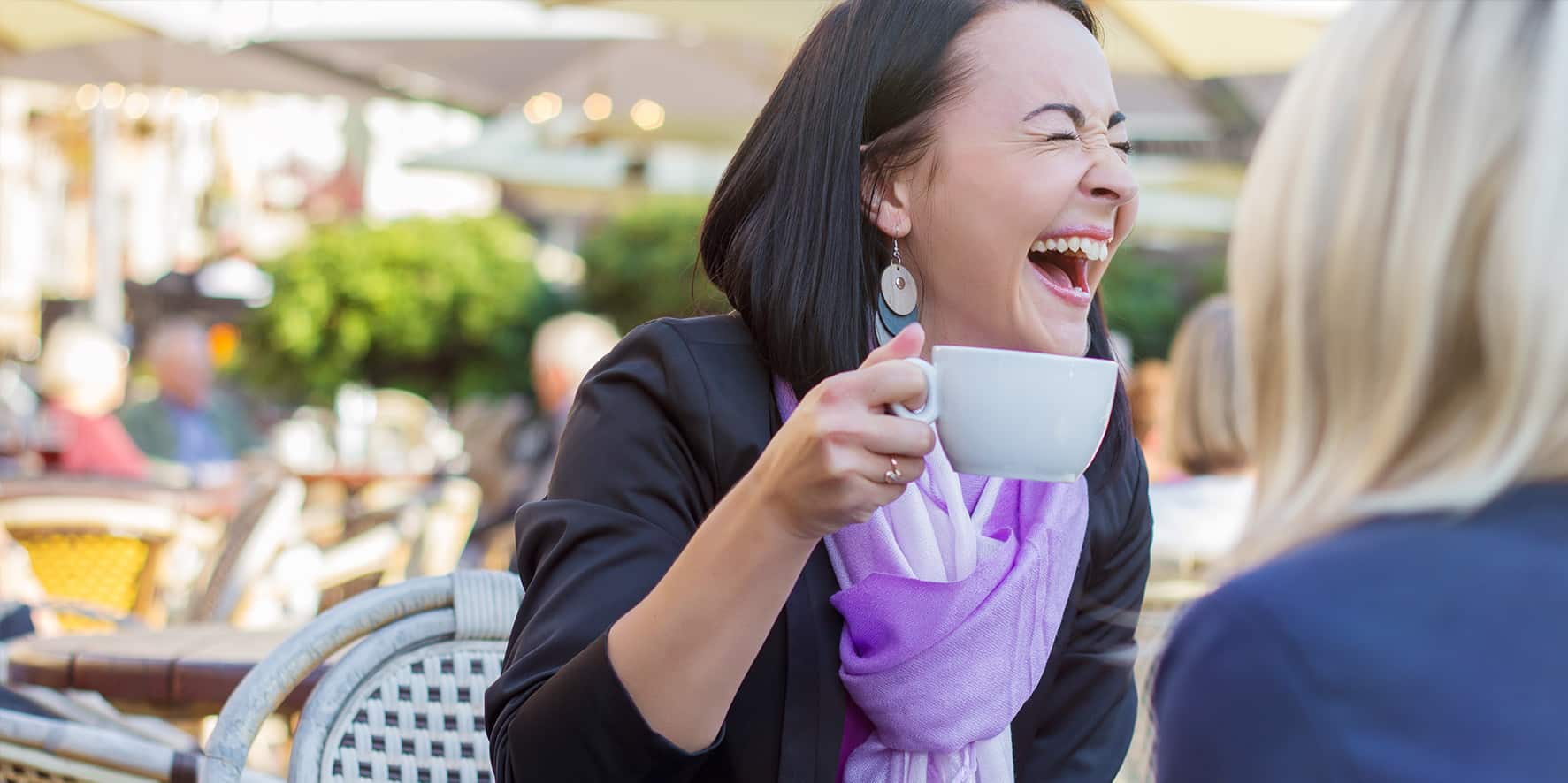 A woman laughs over coffee